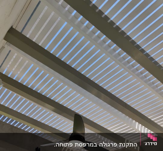 מאוורר תקרה תלוי מתחת לפרגולה מעץ